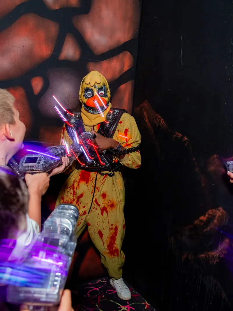 Актёр в хоррор-костюме и дети с бластерами на арене LaserLand