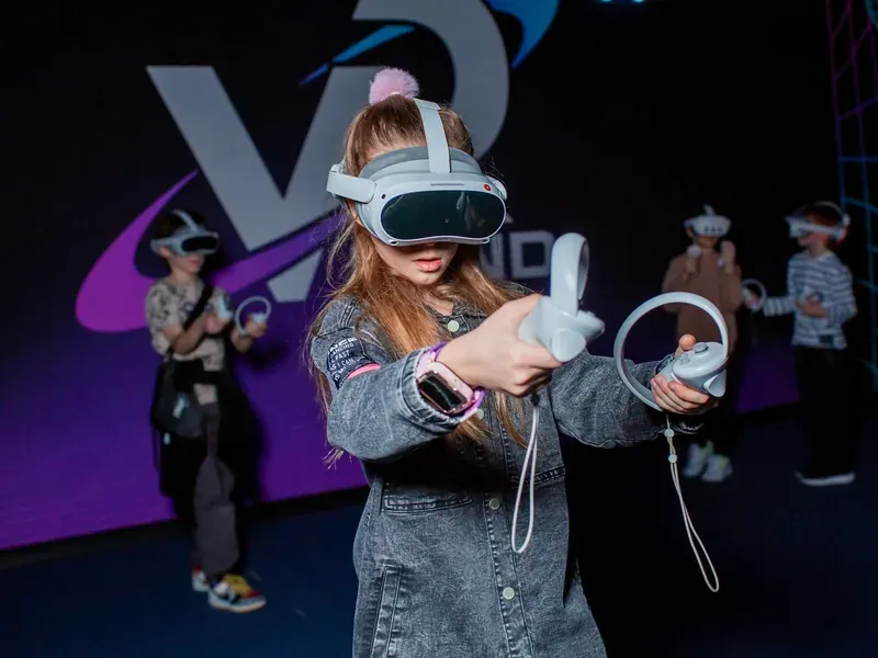 Девочка в VR-шлеме с контроллерами в зоне виртуальной реальности LaserLand